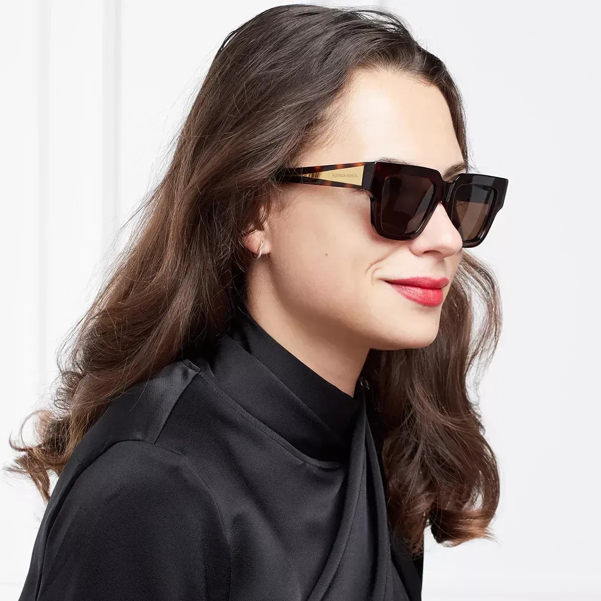 Woman wearing dark tortoiseshell designer sunglasses, side profile, confident expression